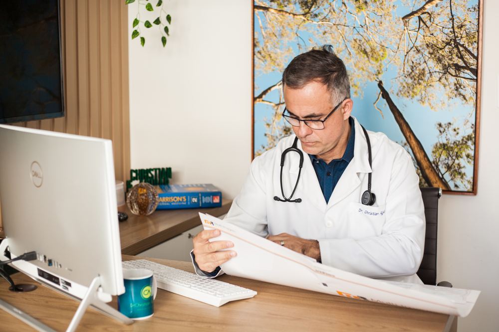 Dr. Christian Aguiar de jaleco, analisando um exame